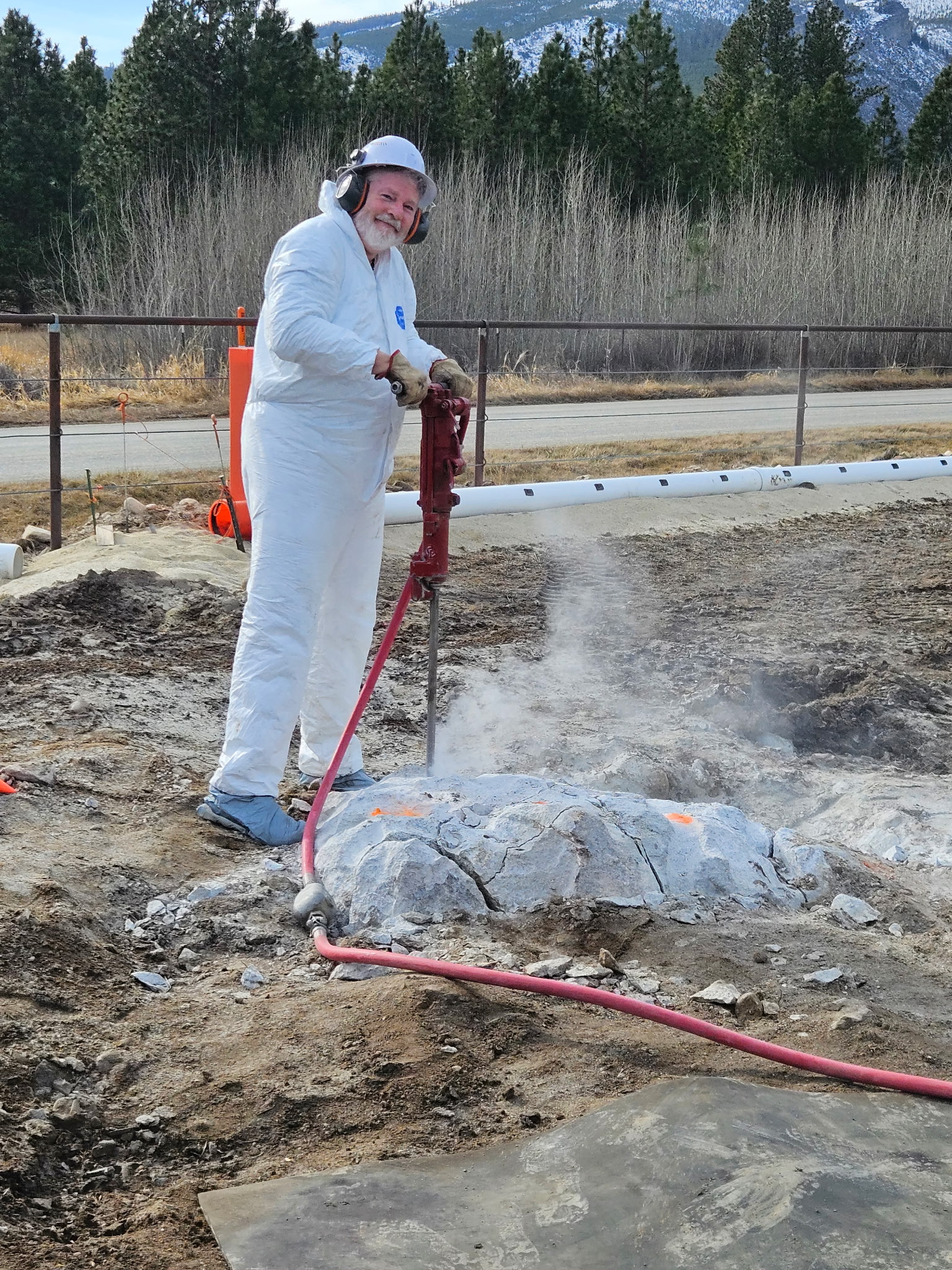 Dan drilling rock on a job site in the mountains